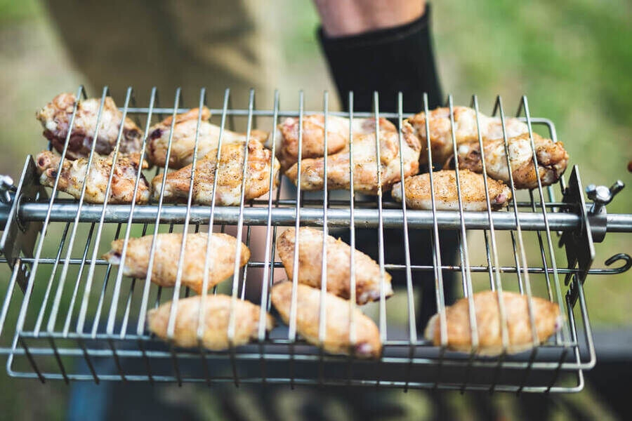 This image shows chicken wings being cooked in a rotisserie basket in an Auspit.