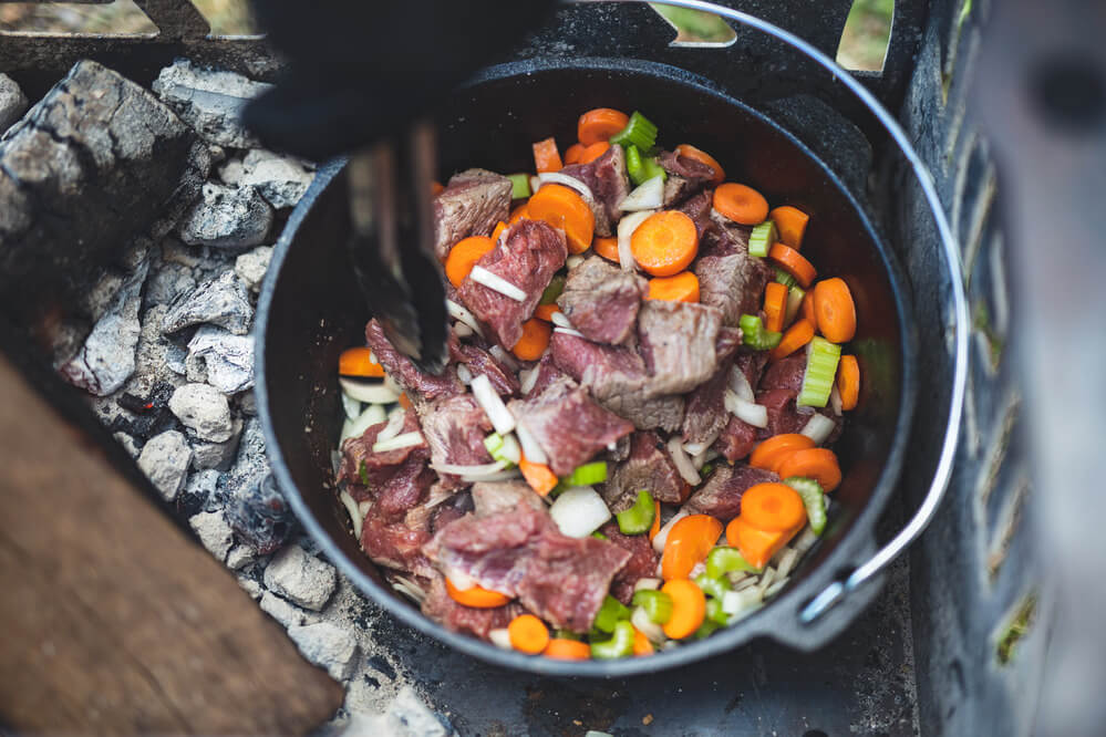 This image shows the Cast Iron Camp Oven cooking beef and veggies.