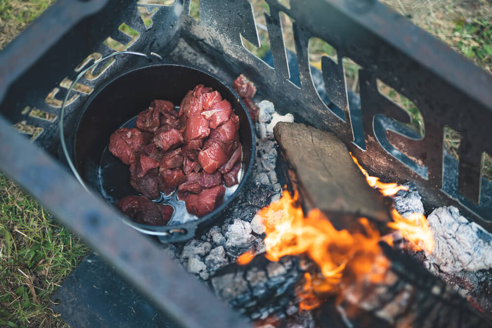 This image shows the Cast Iron Camp Oven cooking beef.