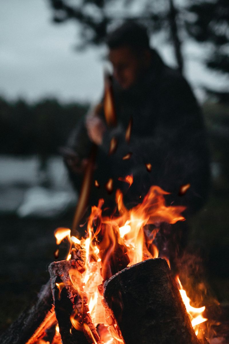 Close-up of campfire flames during a camping game by the river at dusk