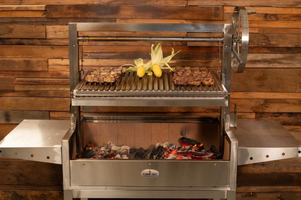 Stainless steel Parrilla BBQ grill with corn and meat cooking over charcoal.