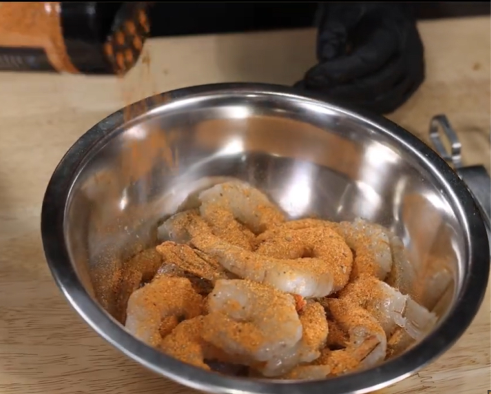 Raw prawns in a stainless steel bowl being seasoned with Flaming Coals Gyros Rub.