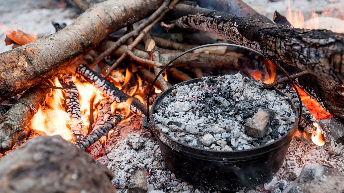 This is a picture of a cast iron camp oven cooking in a campfire