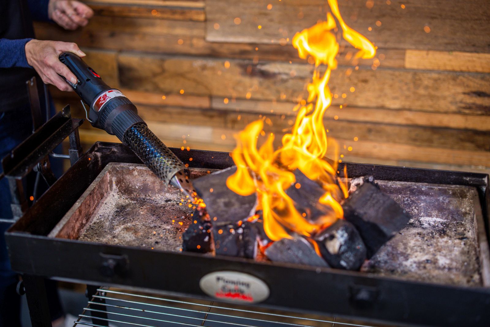 This image shows lump charcoal being lighted with charcoal starter wand